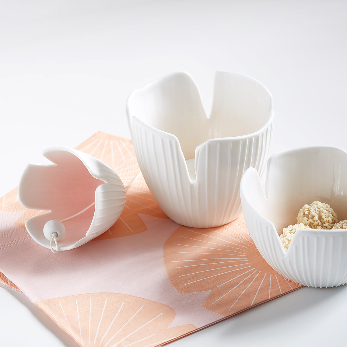 White ceramic bowls on a pink floral mat with a white background
