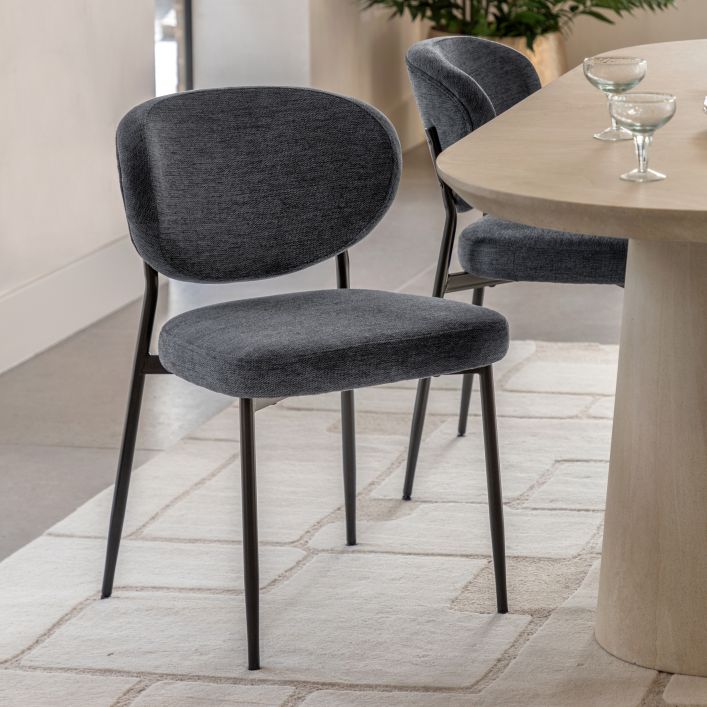 Oppo Dining Chair in dark grey, set of two, displayed beside a wooden dining table with glassware on a light textured rug.