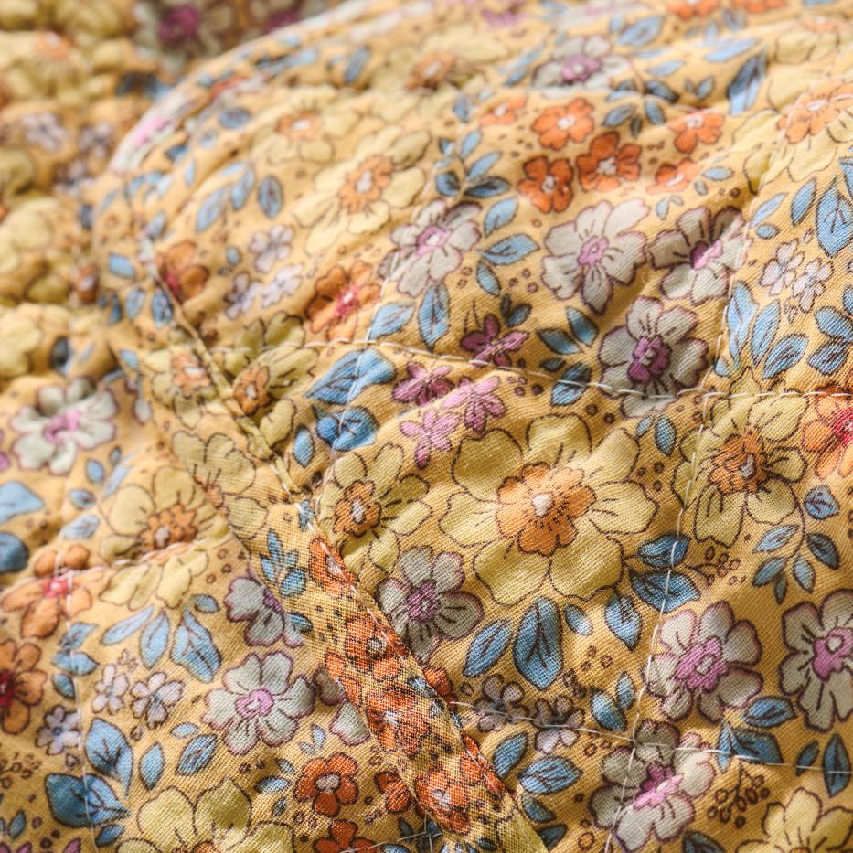 Close-up of a floral fabric with a yellow and multicolor pattern.