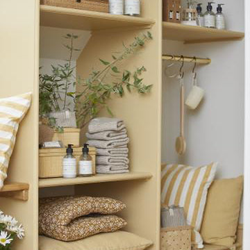 Niche with shelves containing folded clothes, pillows, and decorative items.