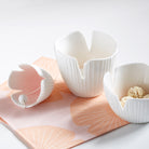 White ceramic bowls on a pink floral mat with a white background