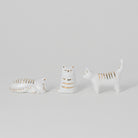 Three ceramic cat figurines on a light gray background