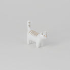 White ceramic cat figurine with gold stripes on a light gray background
