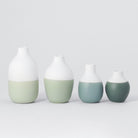 Four ceramic vases with gradient colors on a light gray background