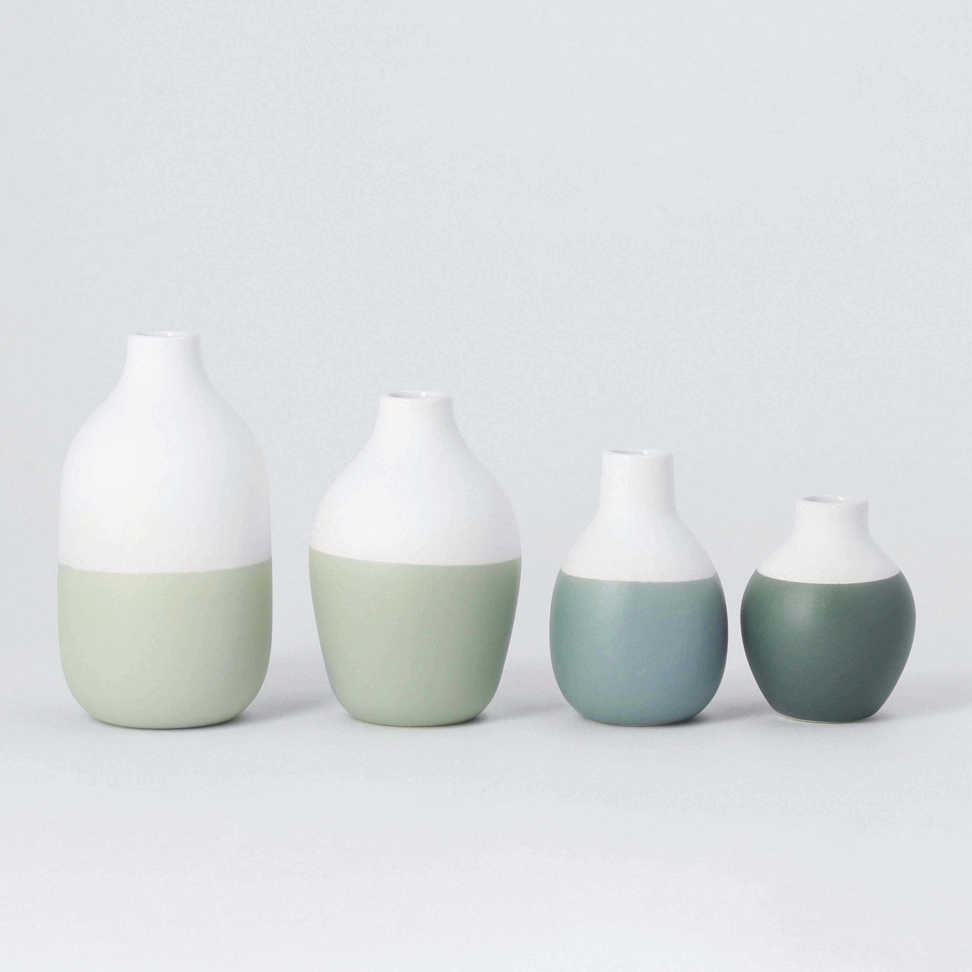 Four ceramic vases with gradient colors on a light gray background