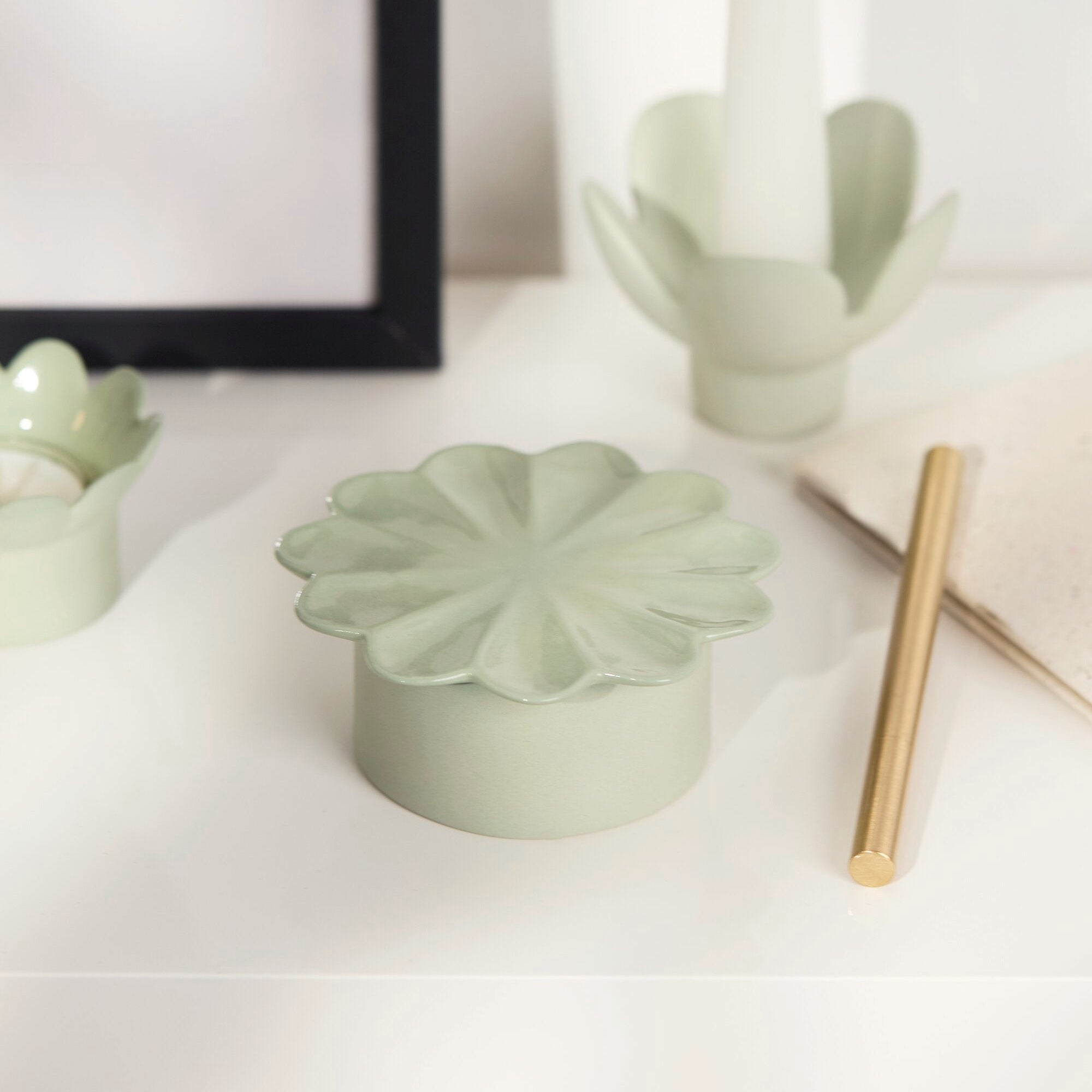 Green ceramic flower-shaped object on a white surface with a blurred background
