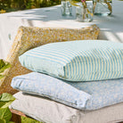 Stack of outdoor cushions on a wooden bench with a garden background