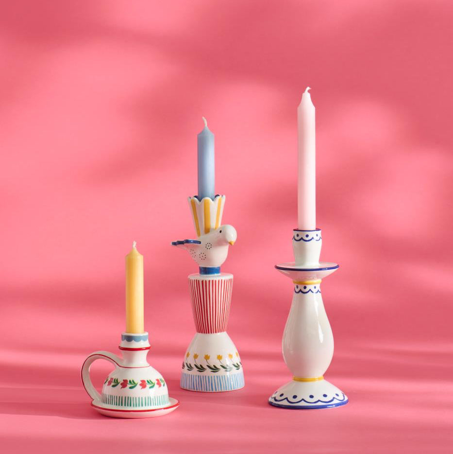 Set of decorative candle holders with candles against a pink background