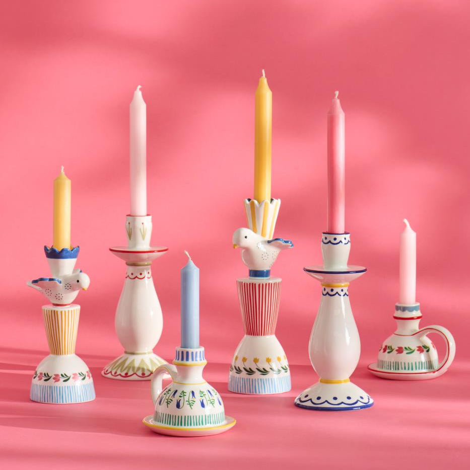 Set of colorful candle holders with candles on a pink background