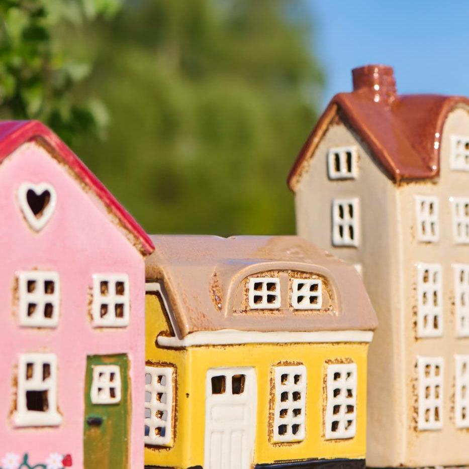 Model houses in pink, yellow, and beige with a blurred green background