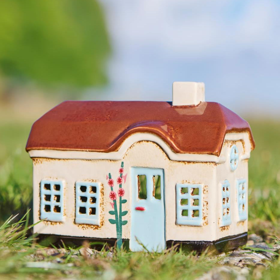 Small model house with a brown roof on grass