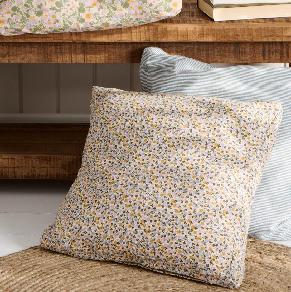 Floral-patterned pillow on a wooden bench with a neutral background