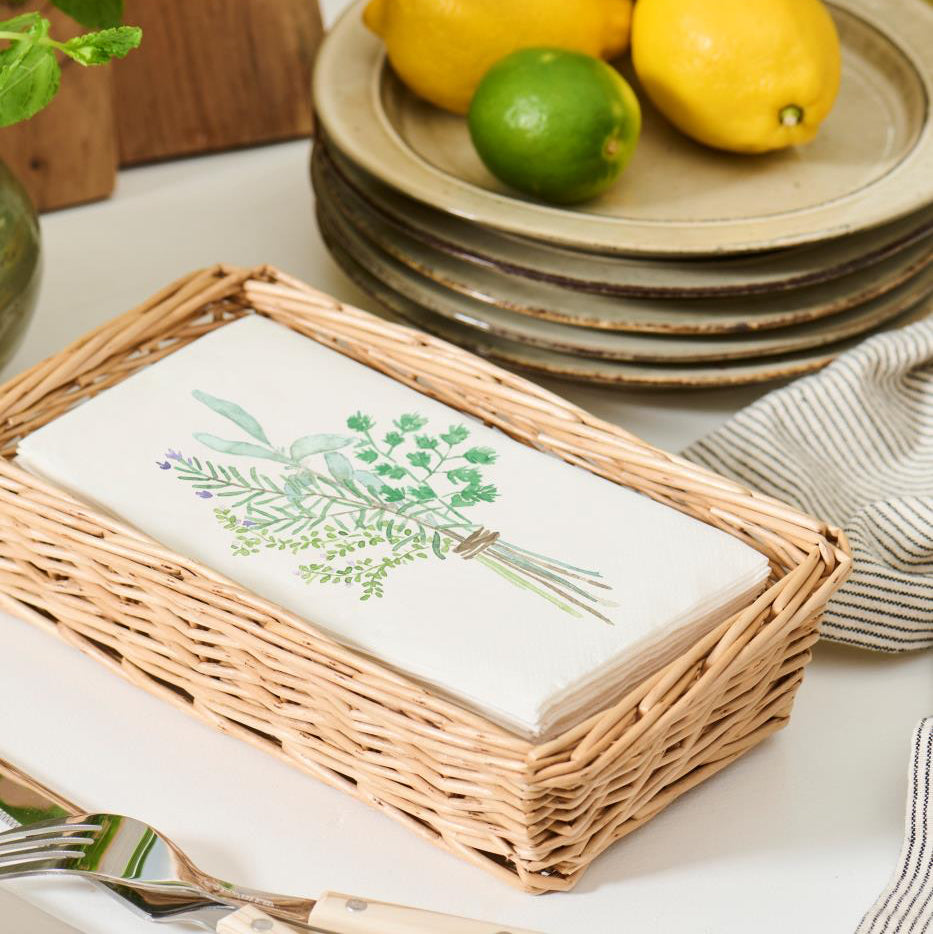 Wicker basket with embroidered towel on a kitchen counter with lemons and limes.