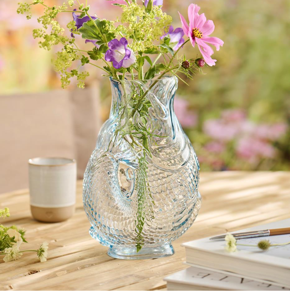 Clear glass vase with flowers on a wooden table outdoors