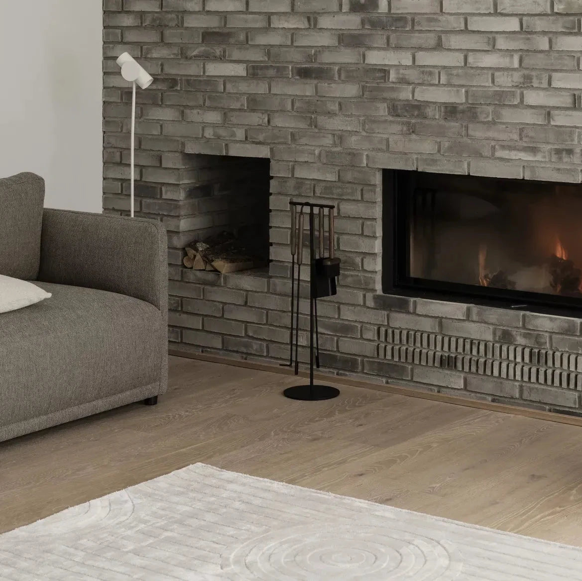 Living room with a brick fireplace, gray sofa, and decorative items.