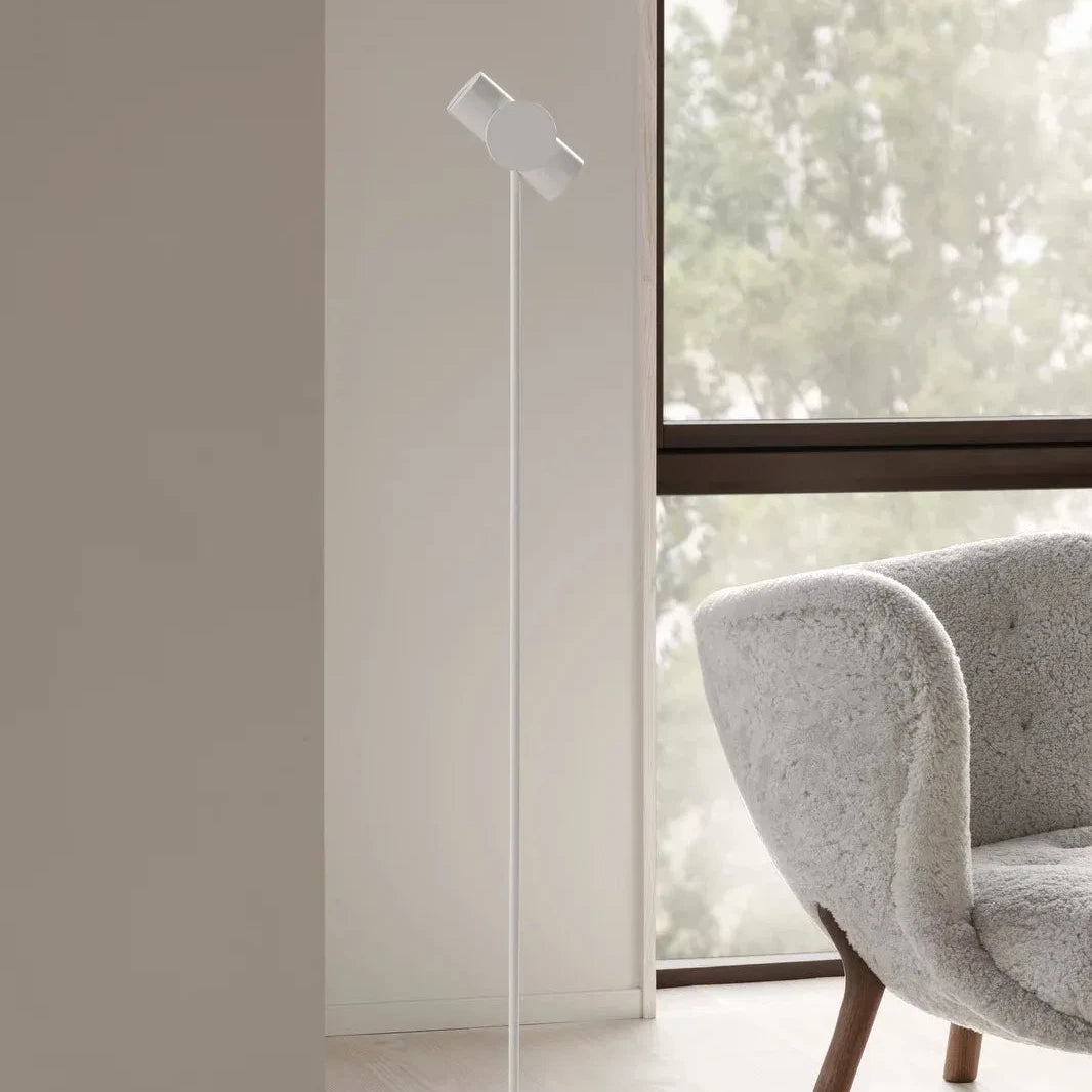 Modern floor lamp in a minimalistic room with a chair and large window.