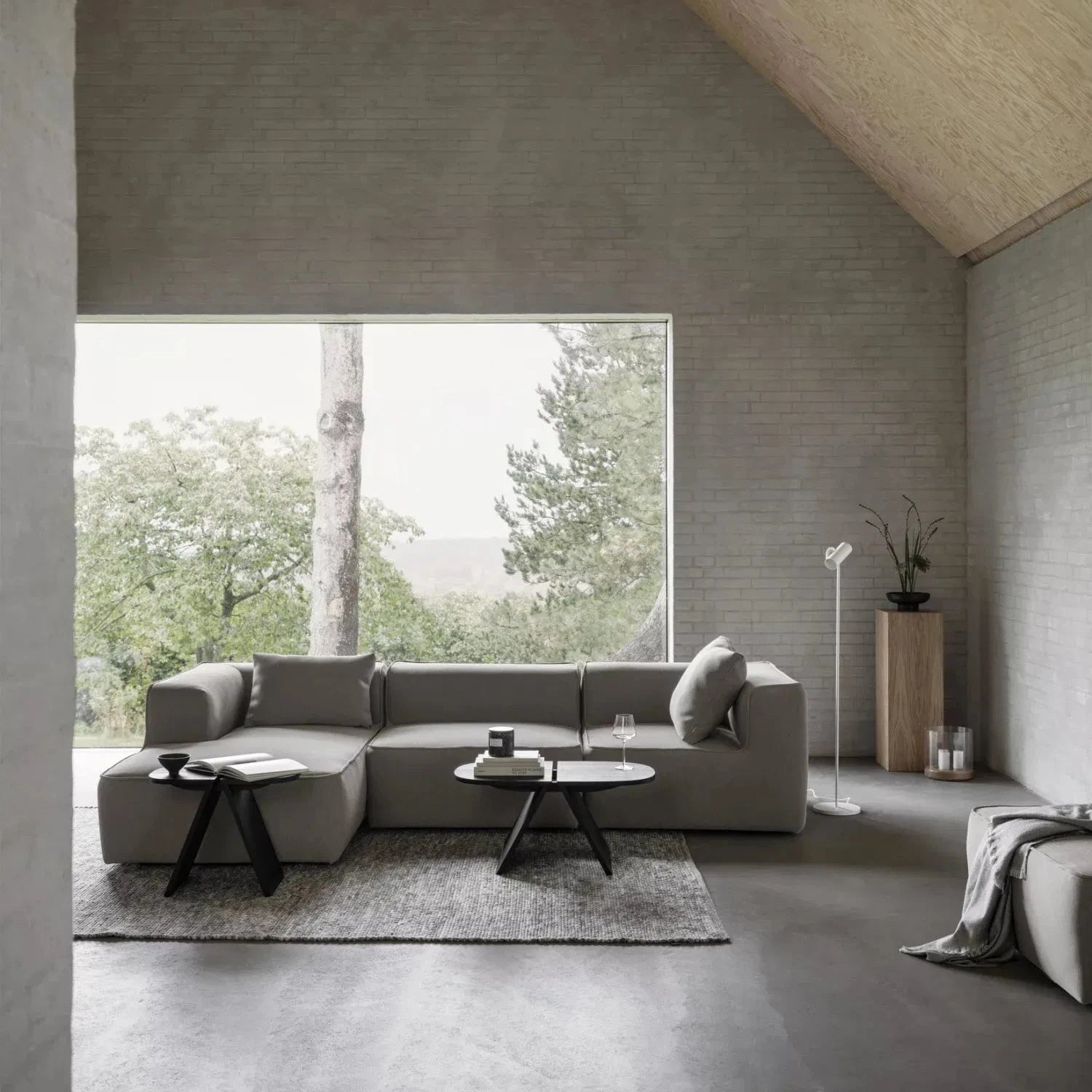 Modern living room with a gray sectional sofa, coffee table, and large window view.