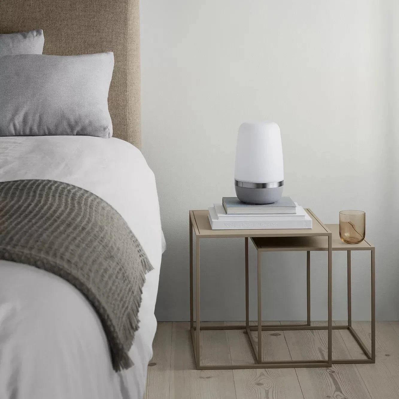 Bedroom with a bed and nightstand featuring a lamp and books.