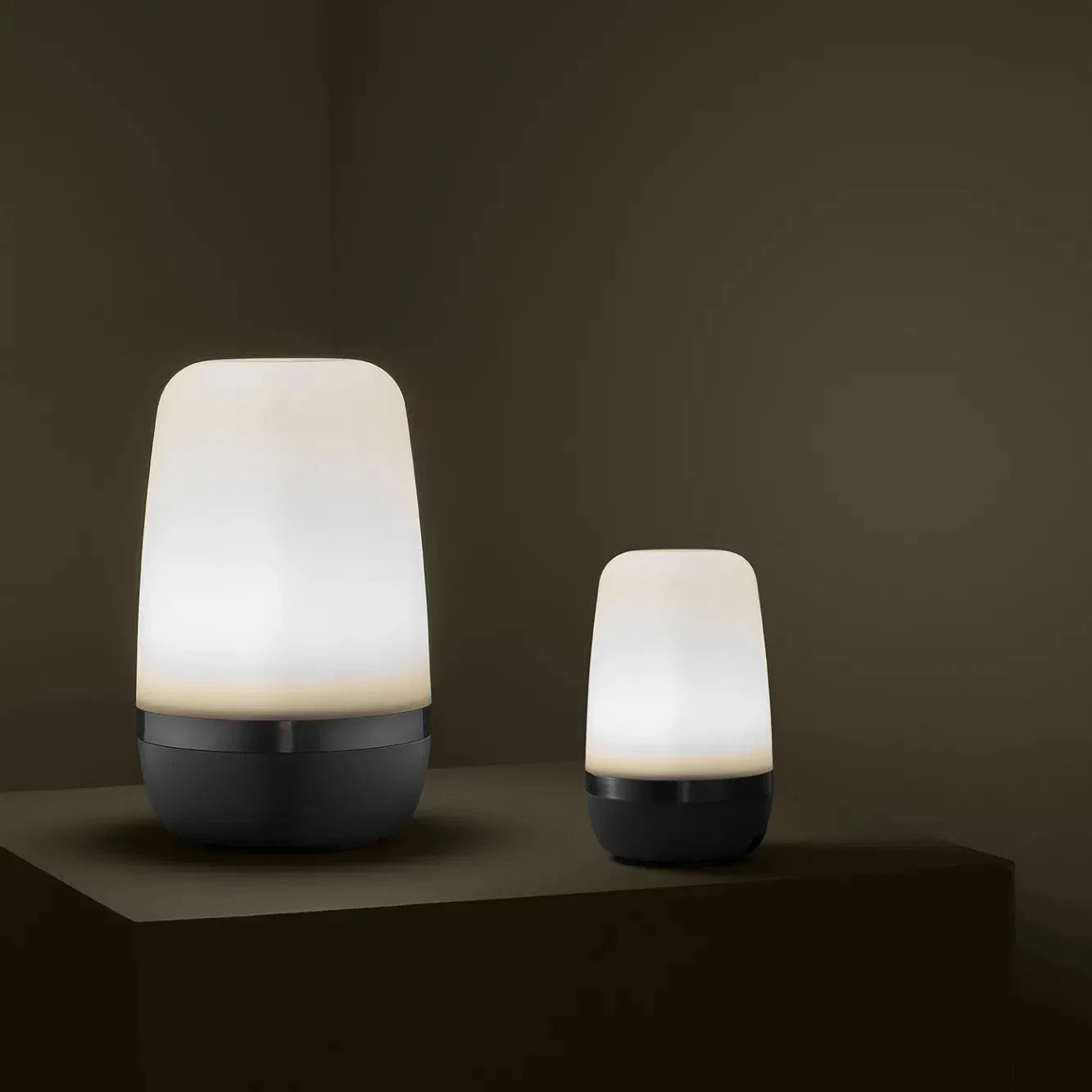 Two illuminated lamps on a dark surface with a dark background