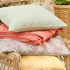 Stack of colorful pillows on a wicker chair with a blurred outdoor background