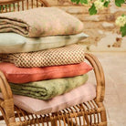 Stack of colorful cushions on a wicker chair with a blurred natural background