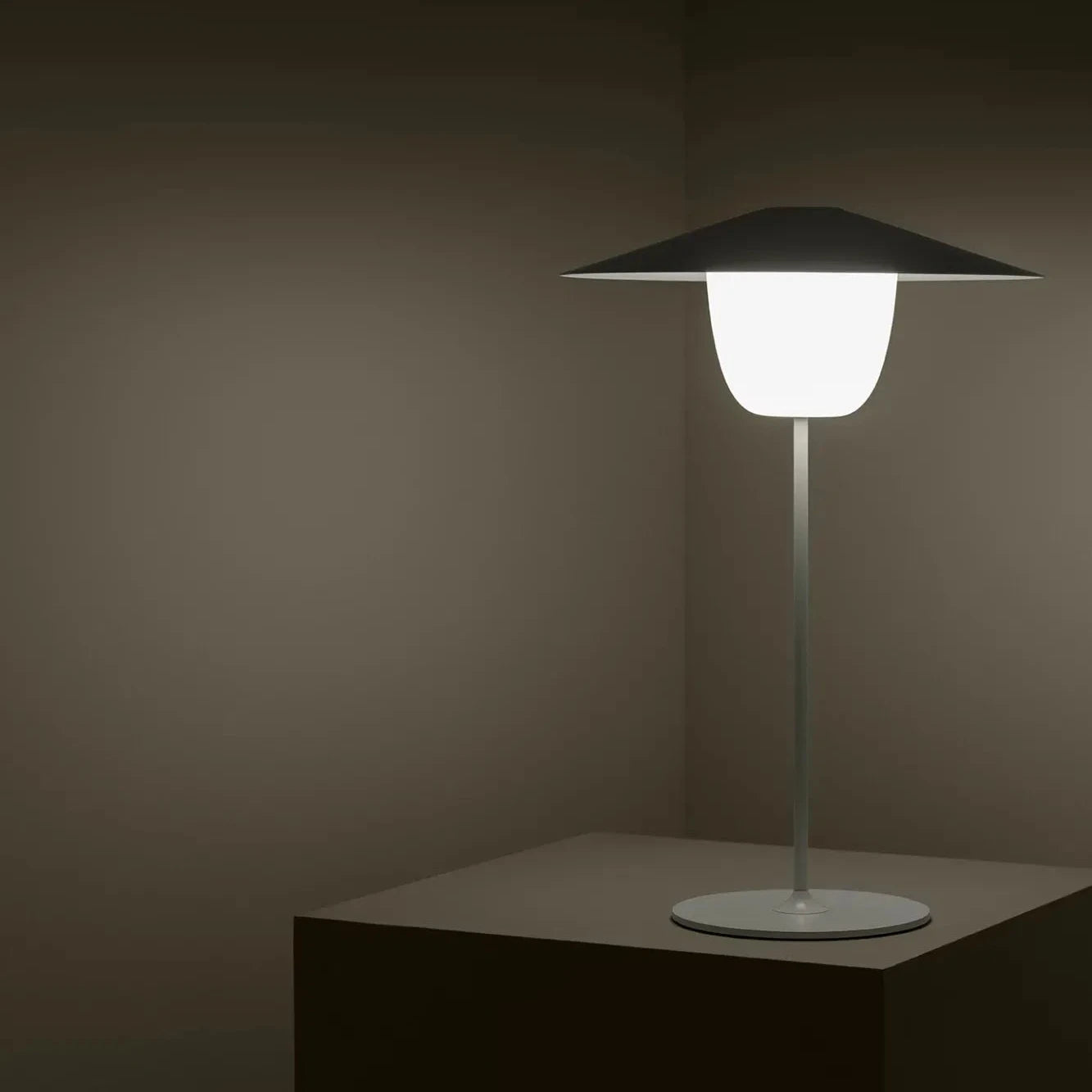 Table lamp with a dark shade on a stand against a dark background
