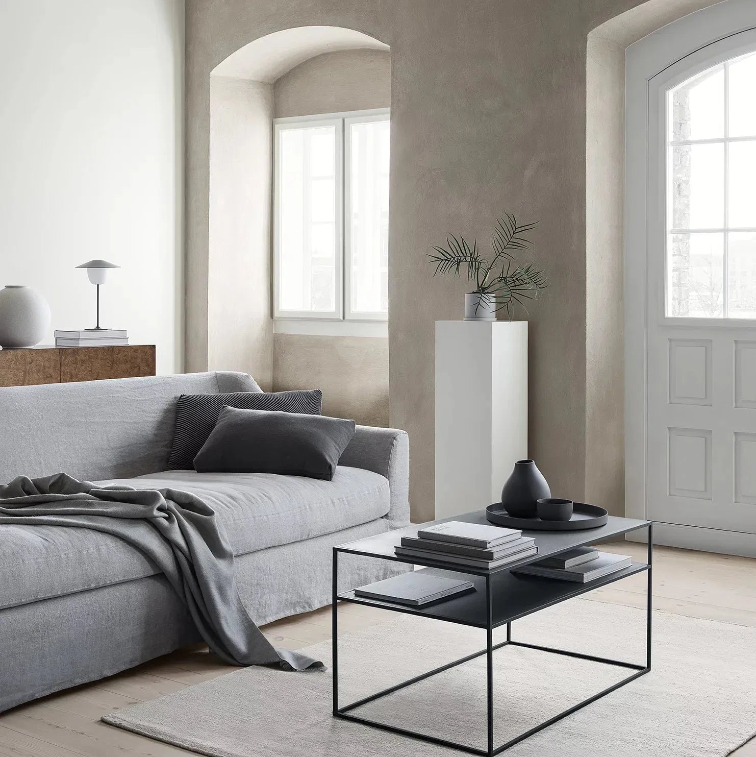 Modern living room with gray sofa, glass coffee table, and wooden beams.