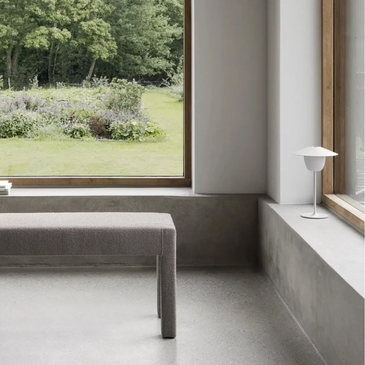 Modern room with a bench, window, and view of greenery