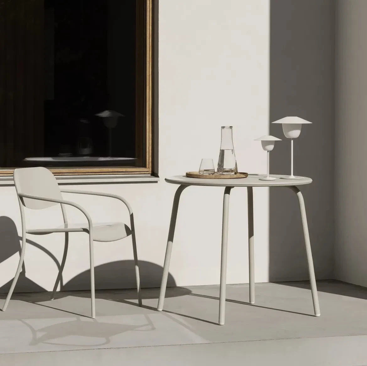 Minimalist indoor setting with a chair and small table against a neutral wall.