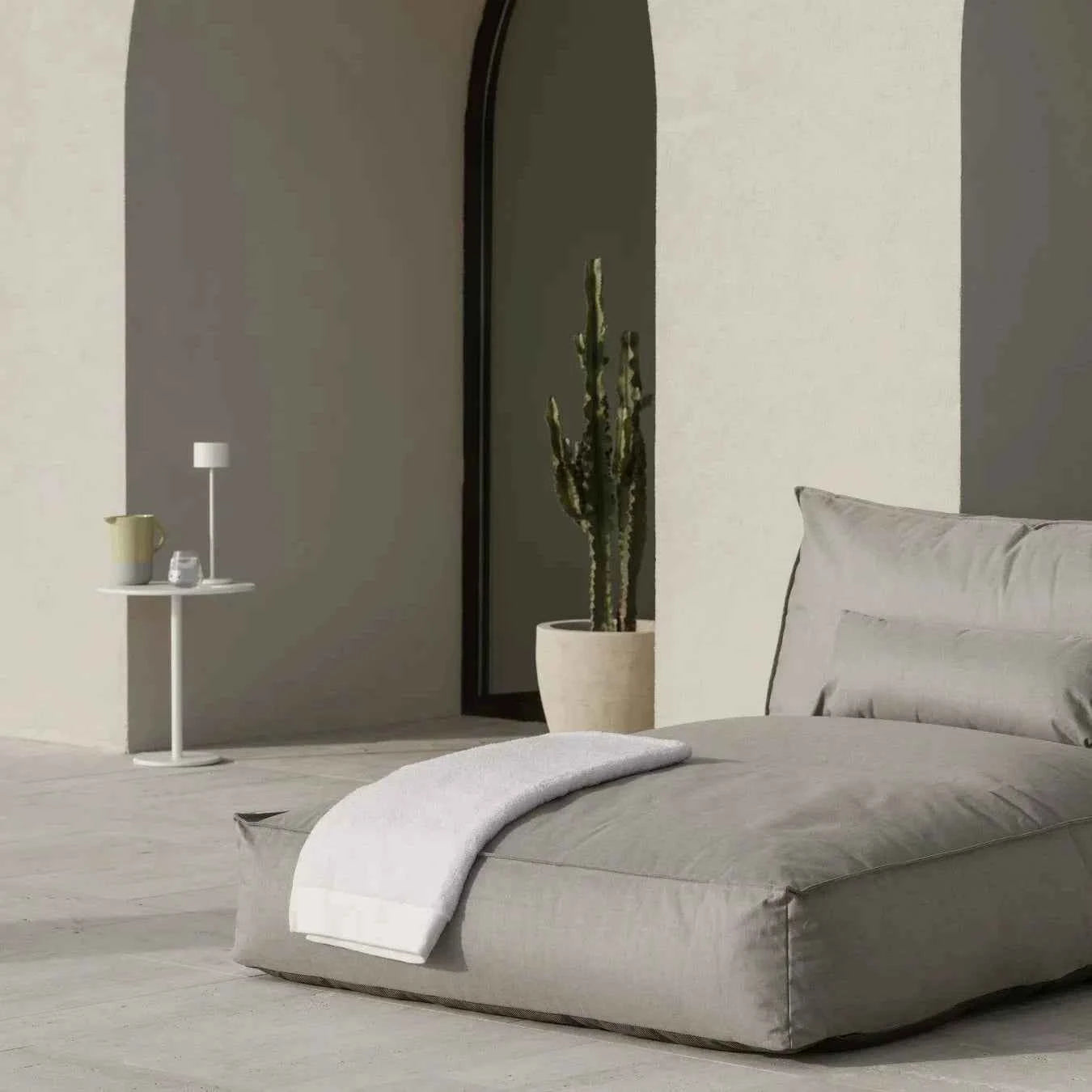 Modern bedroom with gray bed, arched mirror, and minimal decor.