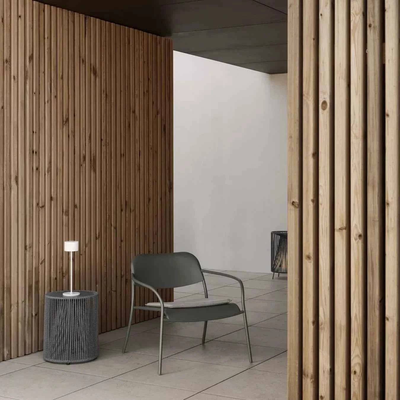 Modern interior with wooden walls, a gray chair, and a small table.
