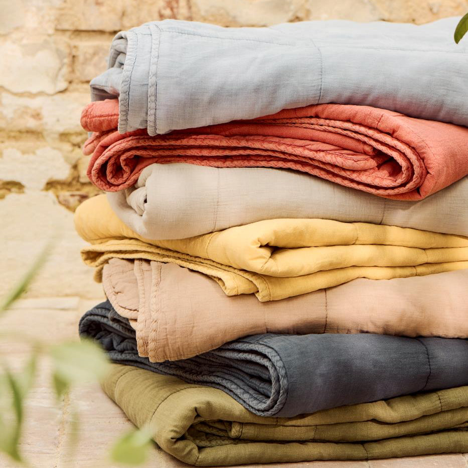 Stack of folded colorful towels on a wooden surface with a stone wall background