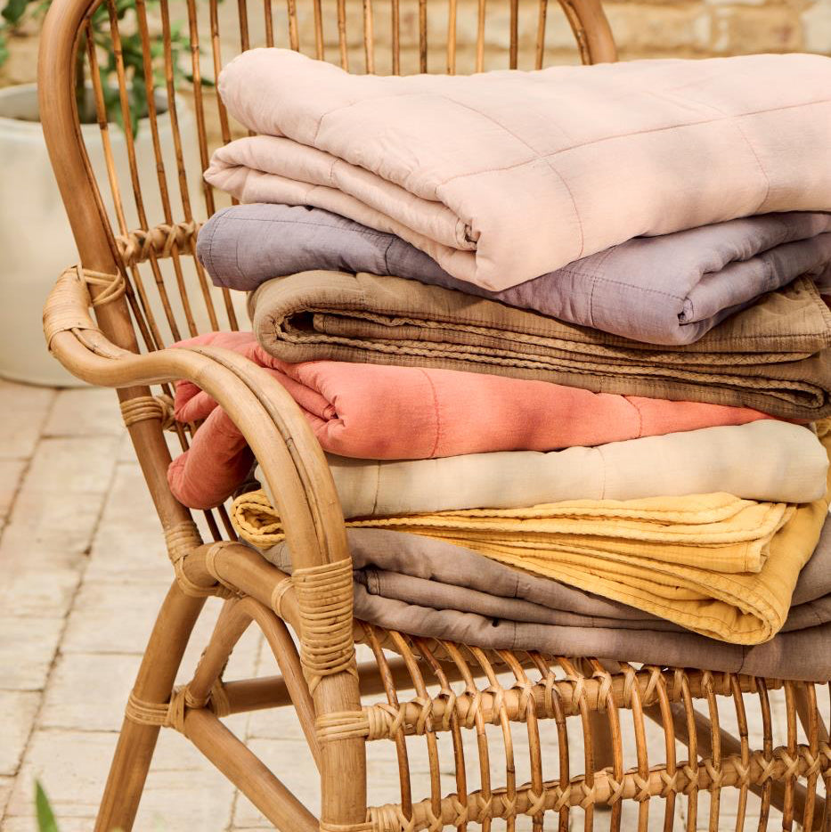 Stack of folded blankets on a wicker chair outdoors