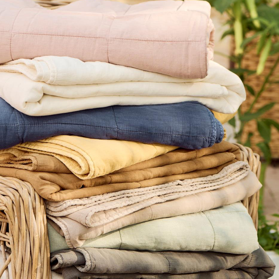 Stack of folded clothes in a wicker basket with a blurred natural background