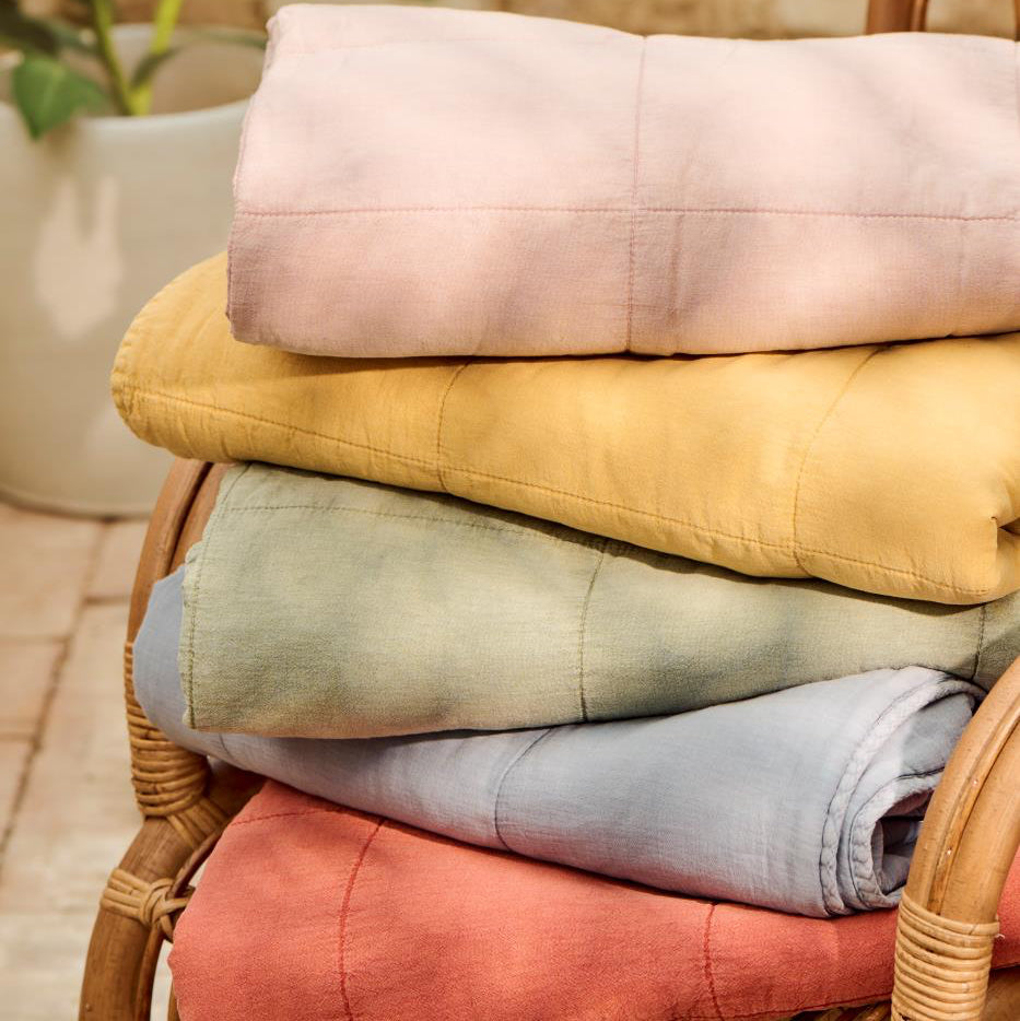 Stack of folded colorful towels on a wicker chair with a blurred natural background