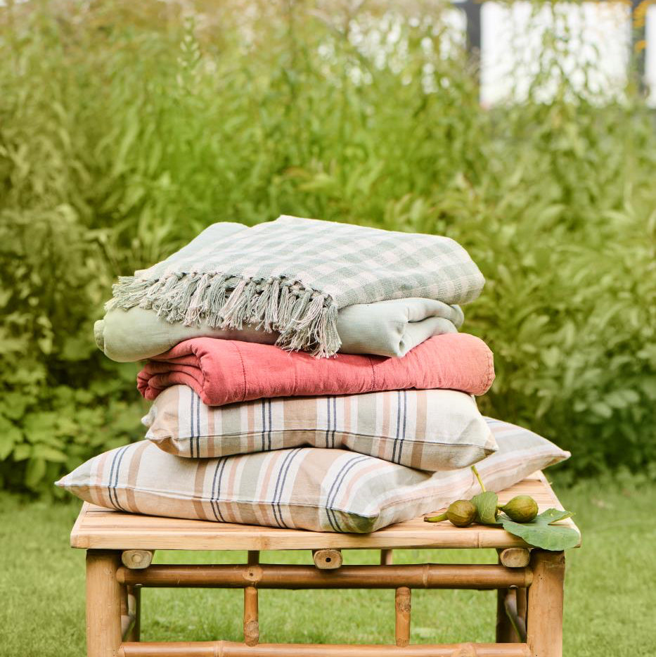 Stack of folded clothes on a wooden bench in a garden