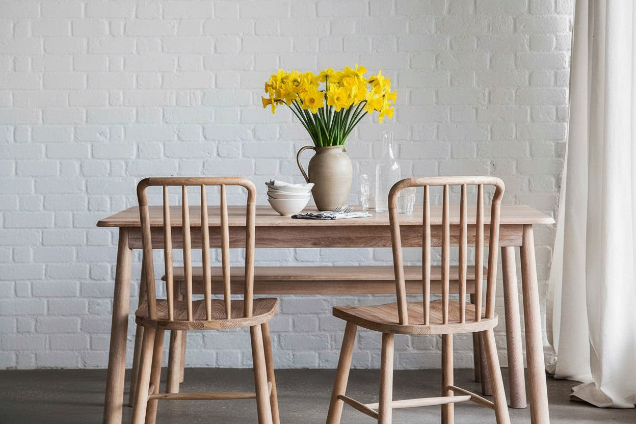Natural wood dining table with spindle-back chairs styled for spring entertaining
